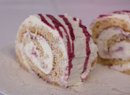 White Swiss roll cake with pink cream in a plateの写真素材