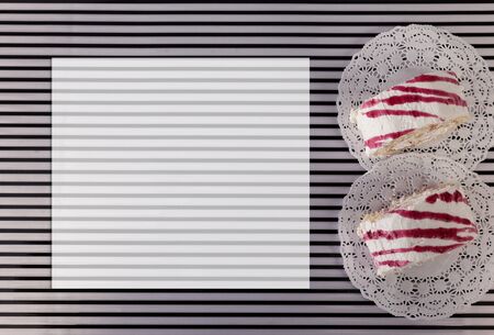 White pastries with pink cream on a striped background.の写真素材