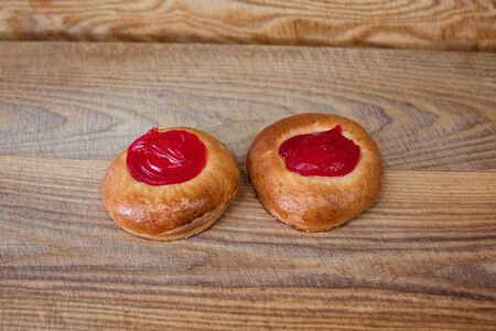 Two round buns with red cream on a tableの写真素材