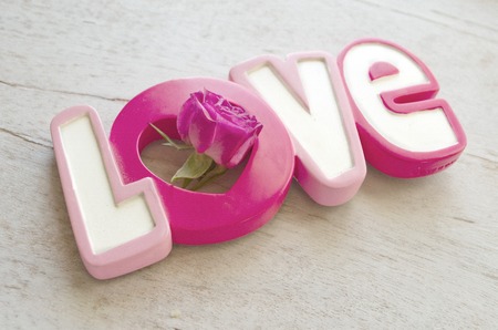 Word love with rose on white wooden background. Valentine day backgroundの写真素材