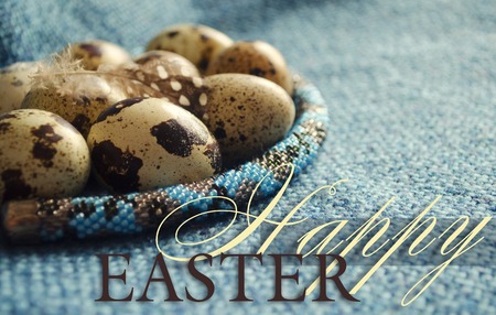 Easter composition with feather, quail eggs and beaded jewellery on woolen fabric. Close up.の写真素材