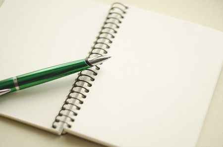 A part of open blank white notebook and green pen on the desk.の写真素材