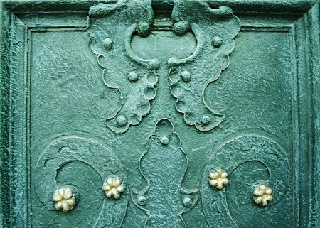 A part of old decorated wrought iron doors. Curved design elements on dark green metal door. Architectural metal background with decorative elements.の写真素材