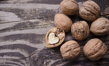Walnuts on a grey textured wooden table. Assortment of nuts isolated on rustic old wooden background and splintered walnut with heart-shaped core. Walnuts close up.の写真素材