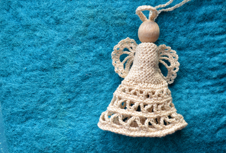 White knitted angel on a blue textile background. Christmas angel in the form of knitted toys, close-upの写真素材