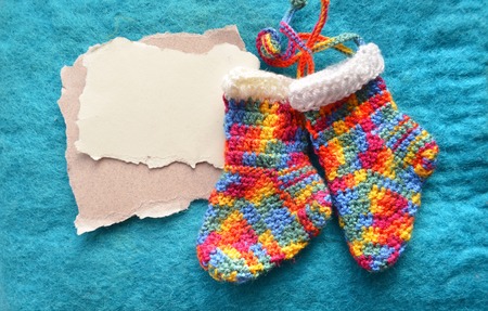 Handmade knitting socks with ornament hanging on ribbon isolated on blue. Decorative collage with place for text. Idea for poster,banner,flyer.Christmas colored boots in anticipation of Santa's giftsの写真素材