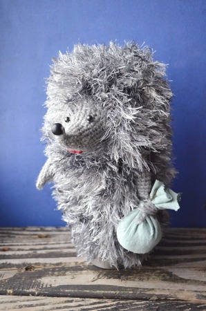 Soft toy hedgehog. Handmade knitted hedgehog isolated on blue background.の写真素材