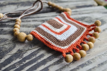 Handmade accessories in ethnic style on wooden table. Crochet homemade things. Crochet pattern. Handicraft manufacturing.の写真素材