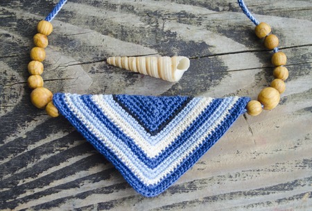 Handmade accessories in ethnic style on wooden table. Crochet homemade things. Crochet pattern. Handicraft manufacturing.の写真素材