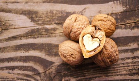 Walnuts on a textured wooden table. Assortment of nuts isolated on rustic old wooden background and...