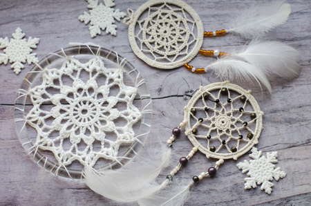 Dreamcatcher with feathers on a wooden background. Ethnic design, boho style, tribal symbol.White Christmas and New Year snowflake on a wooden vintage old background.の写真素材