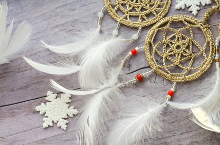 Dreamcatcher with feathers on a wooden background. Ethnic design, boho style, tribal symbol.White...