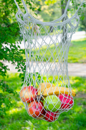 Trendy string bag with fruits. Shopping bag. Trendy closeup for lifestyle design. Fresh fruit. Cloth bag. Ecological bag - an alternative to polyethylene bags.の写真素材