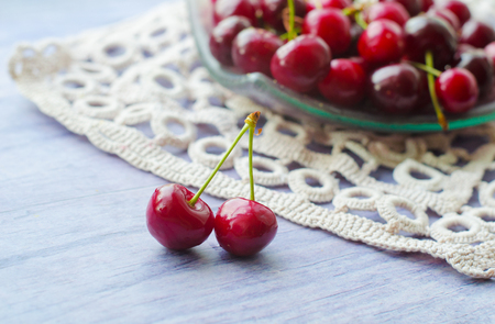 Fresh ripe cherries on wooden table. Cherries in a transparent glass plate and kitchen napkin.の写真素材