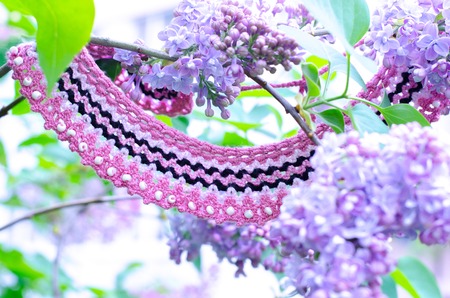Purple lilac bush an crochet handmade accessories. Handicraft manufacturing. Spring branch of blossoming lilac.の写真素材