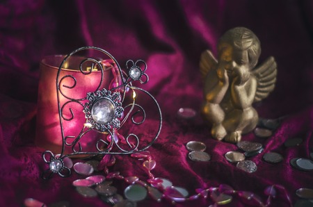 Vintage metal heart with a crystal on a background of violet drapery with lights of the garland....