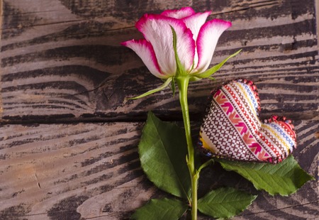 Beautiful rose on brown wooden background and fabric heart.の写真素材