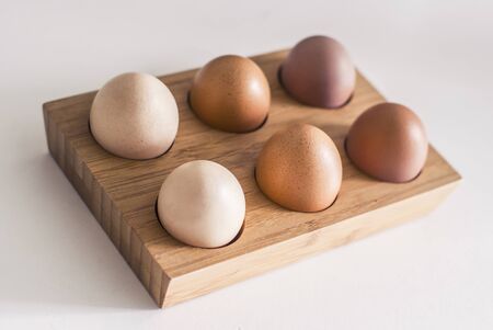 Wooden holder with chicken eggs on table. Six brown eggs.の写真素材