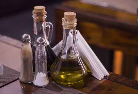 Bottles with olive oil, balsamic vinegar, pepper and salt shaker on restaurant table.の写真素材