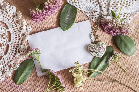 Sedum Spectabile and vintage brass pendant made of enamel hearts.Crocheted napkin on a pink background.の写真素材
