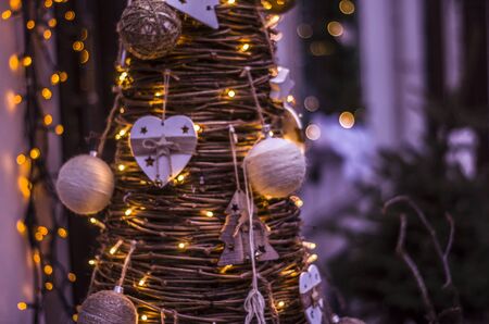 Christmas tree from wooden branches with ornaments and garlands.Abstract bokeh blurred color light background.の写真素材