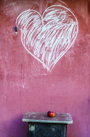 Red apple on stool and heart drawing with chalk. Conceptual photo.の写真素材