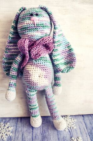 A knitted rabbit in pastel colors. Vintage photo of handmade toys.の写真素材