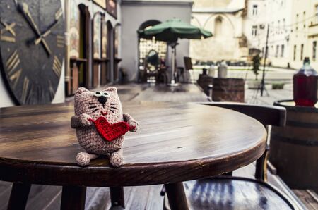 Adorable crocheted cat with red heart on old city background.Valentine day concept.の写真素材