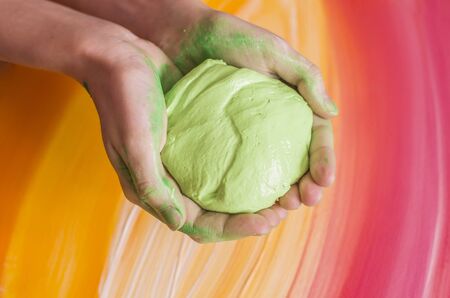 Light green slice in hands on a picturesque background. Toy for children photo.の写真素材