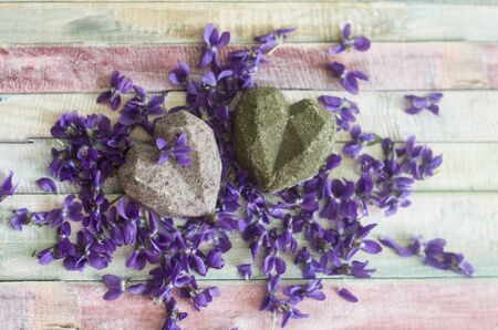Organic handmade soap shampoo on purple flowers background. Picturesque background with violets.