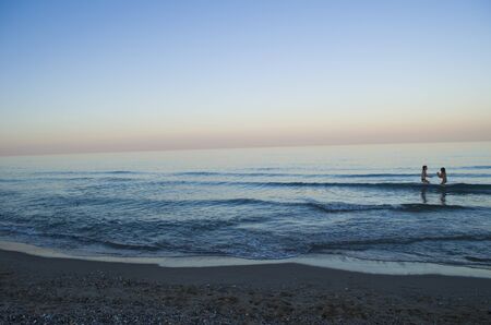 Silhouette of a child on the background of the evening sea. Seaside summer landscape photo.の写真素材