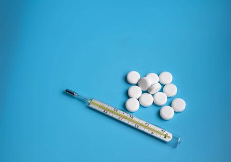 thermometer and white pills on the blue backgroundの写真素材