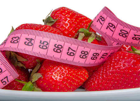 Red fresh strawberry with pink tape measure isolated on the whiteの写真素材
