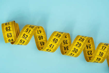 Yellow spiral tape measure on blue background