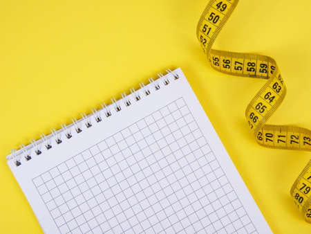 Yellow tape measure centimetric with paper note on yellow backgroundの写真素材