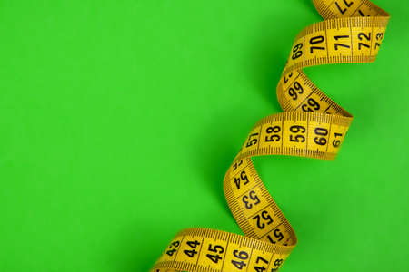 Yellow spiral tape measure on green backgroundの写真素材