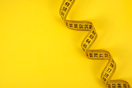 Yellow tape measure centimetric with copy space on yellow background