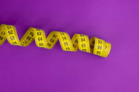Yellow tape measure on the violet backgroundの写真素材