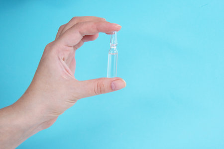 Ampoule vaccine  in hand on blue background