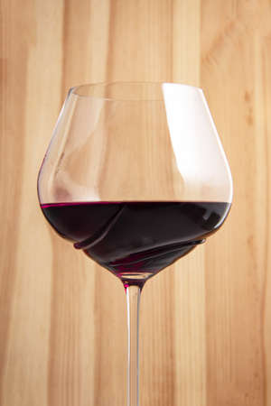 Elegant wineglass with red wine on bright vintage wooden backgroundの写真素材