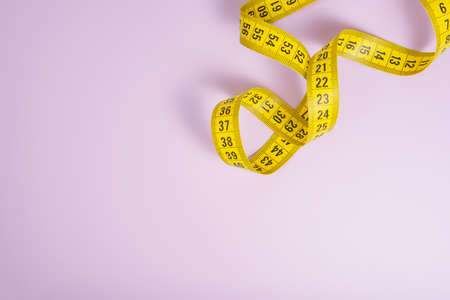 Yellow spiral tape measure on violet background with copyspaceの写真素材