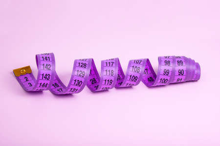 Bright purple tape measure on violet background with copyspaceの写真素材