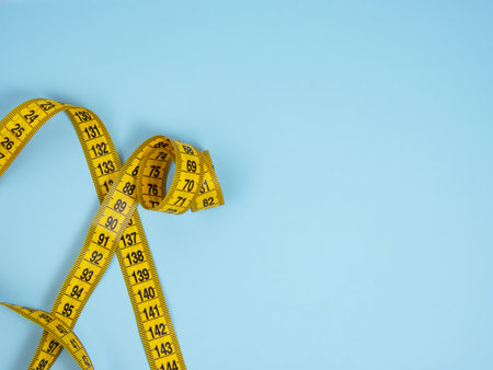 Yellow spiral tape measure on blue bright background