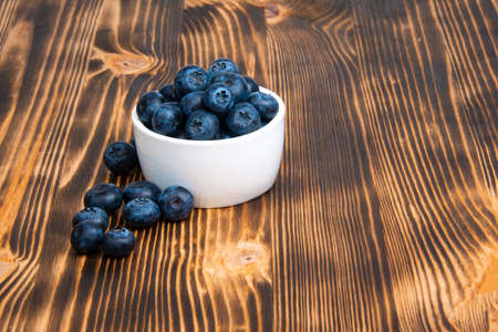 Fresh blueberry in white dish on wooden background copyspace
