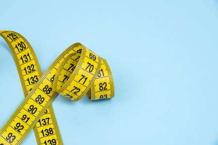 Yellow spiral tape measure on blue bright backgroundの写真素材