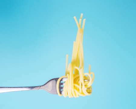 Pasta on fork tasty on blue background with copy spaceの写真素材