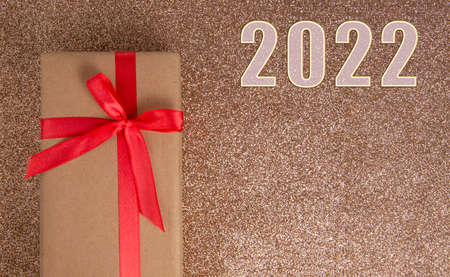 Craft gift box green color bow on shiny 2022 background with copyspace