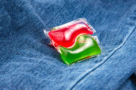 Red green capsule for cloth washing liquid powder on cotton denim backgroundの写真素材