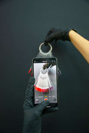 Multicolor different palette gel varnishes examples for manicure in hand on dark backgroundの写真素材