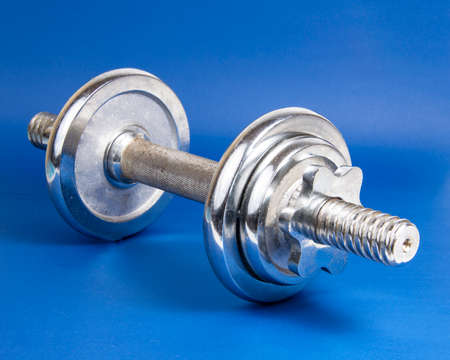 Stainless metal dumbbell on dark blue background with copyspace for textの写真素材